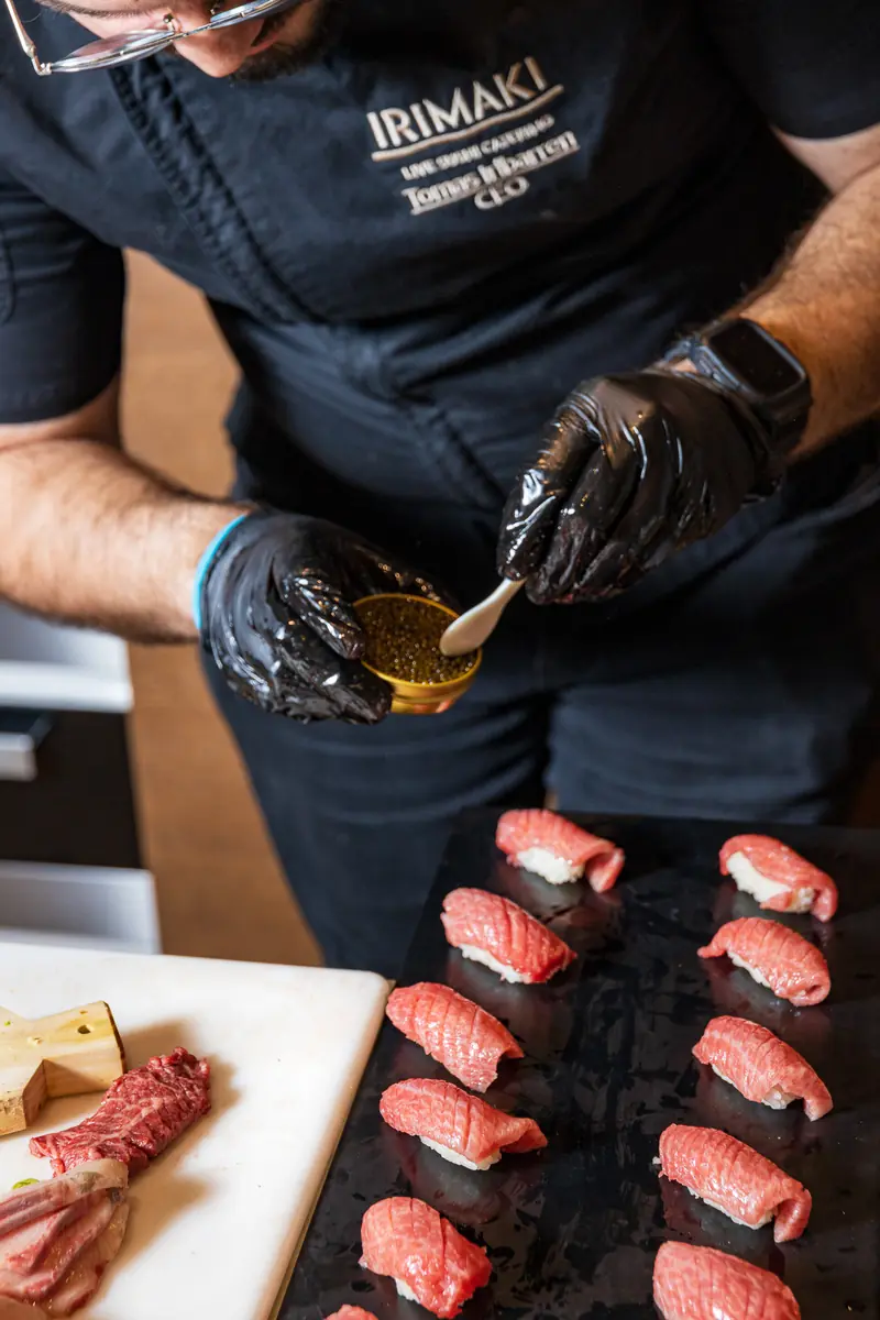 A chef finishing nigiri with caviar