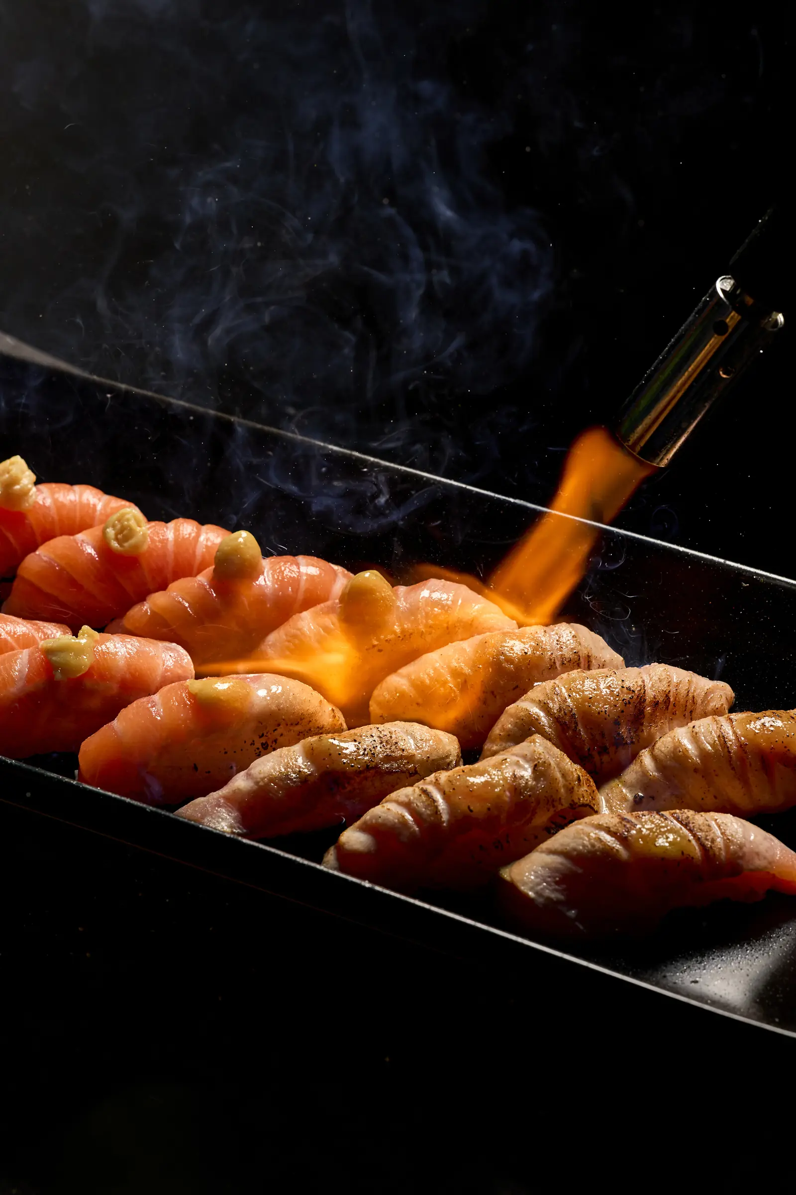 A chef torching salmon nigiri